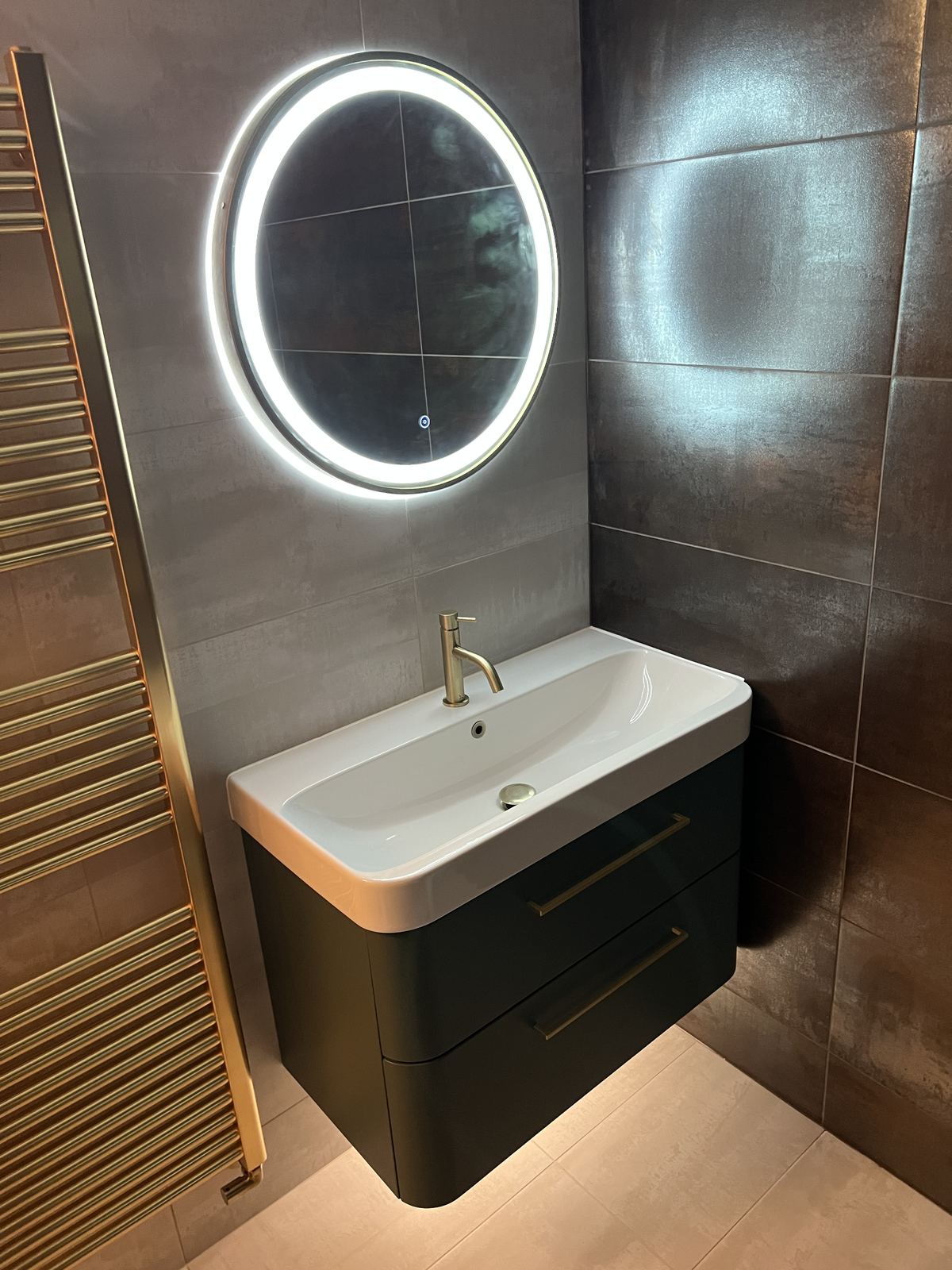 Round LED mirror above a charcoal wall-hung vanity