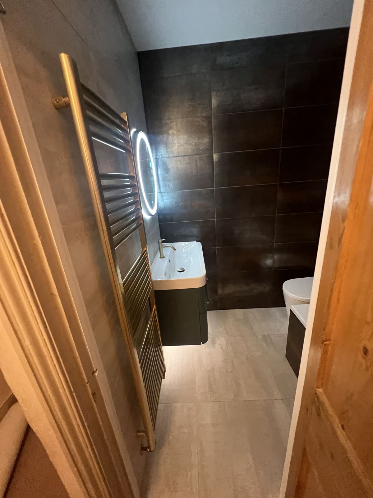 Bronze-tiled bathroom with a light wood-effect floor