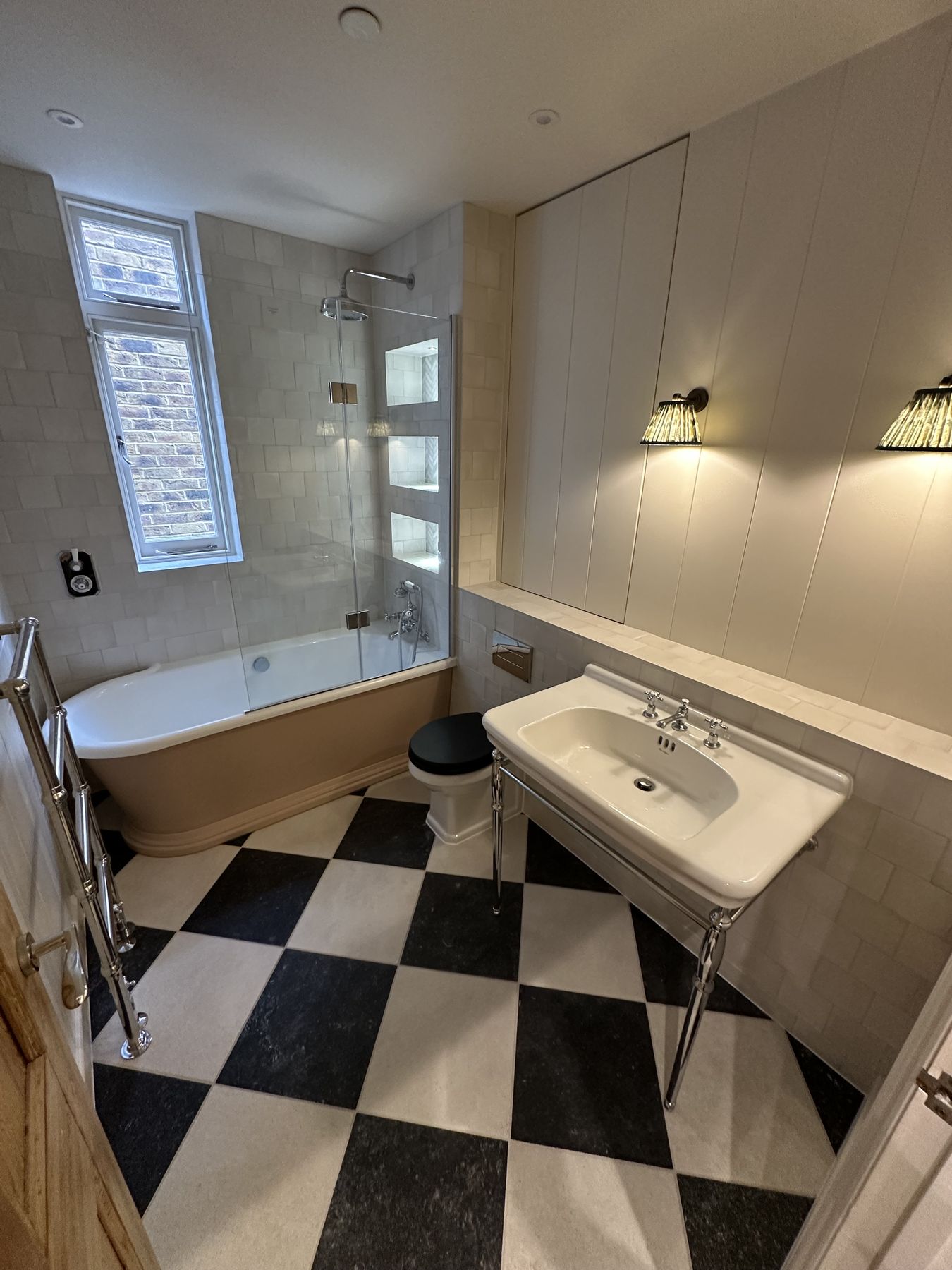 Period family bathroom with a black and white chequerboard floor and a chrome washstand