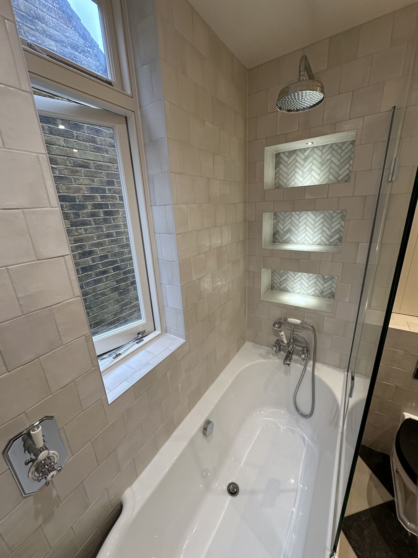 Bath with a glass screen and lit glass shelving